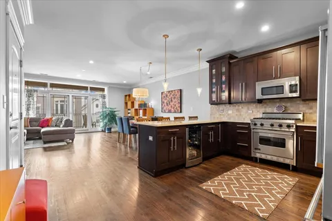 a kitchen with kitchen island granite countertop a stove top oven a sink dishwasher a dining table and chairs with wooden floor