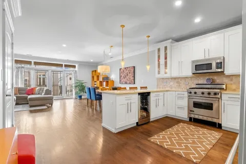 a kitchen with kitchen island granite countertop a stove top oven a sink dishwasher a dining table and chairs with wooden floor