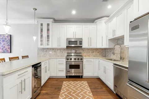 a kitchen with granite countertop white cabinets and stainless steel appliances