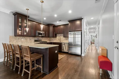 a kitchen with stainless steel appliances kitchen island granite countertop a table chairs refrigerator and microwave
