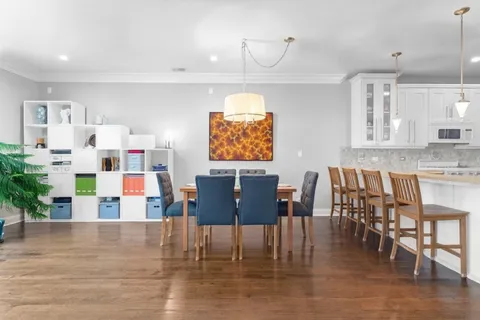 a view of kitchen with stainless steel appliances granite countertop a dining table chairs and white cabinets next to a window