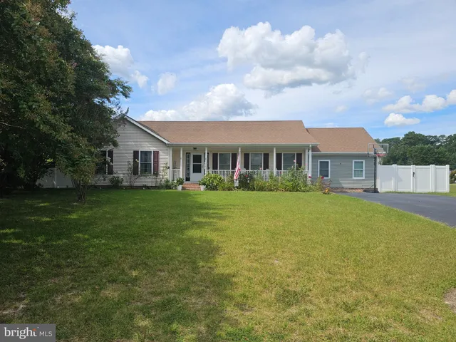 a front view of house with yard and trees in the background