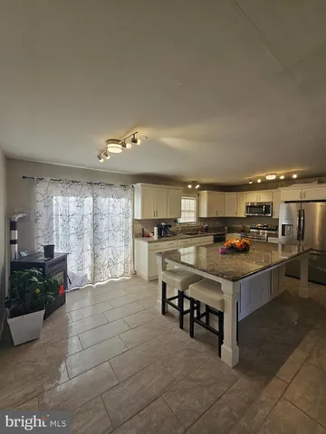 a room with kitchen island stainless steel appliances a sink and cabinets