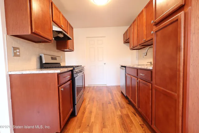 a kitchen with stainless steel appliances granite countertop a refrigerator a stove a sink and dishwasher with wooden floor