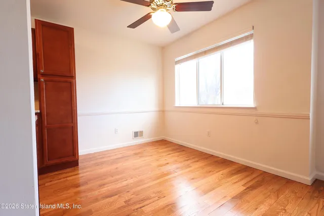 an empty room with chandelier fan and windows