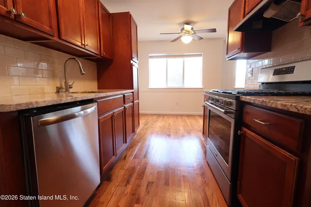 a kitchen with stainless steel appliances granite countertop a stove a sink dishwasher and a refrigerator with wooden floor