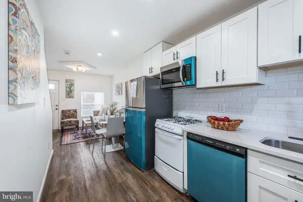 a kitchen with a sink dishwasher stove and white cabinets with wooden floor