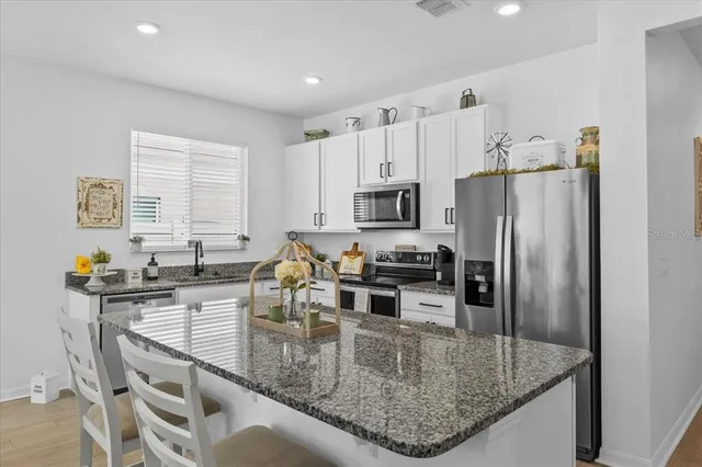 a kitchen with stainless steel appliances granite countertop a sink a stove and a refrigerator