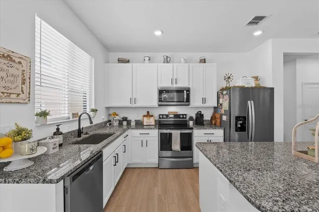 a kitchen with granite countertop a sink a counter top space appliances and cabinets