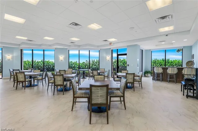 a room with lots of tables a large window and chairs