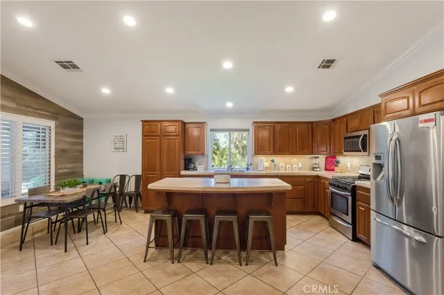 a kitchen with stainless steel appliances kitchen island granite countertop a dining table and chairs