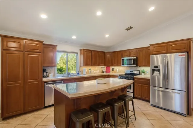 a kitchen with stainless steel appliances granite countertop a refrigerator a sink a stove a dining table and chairs