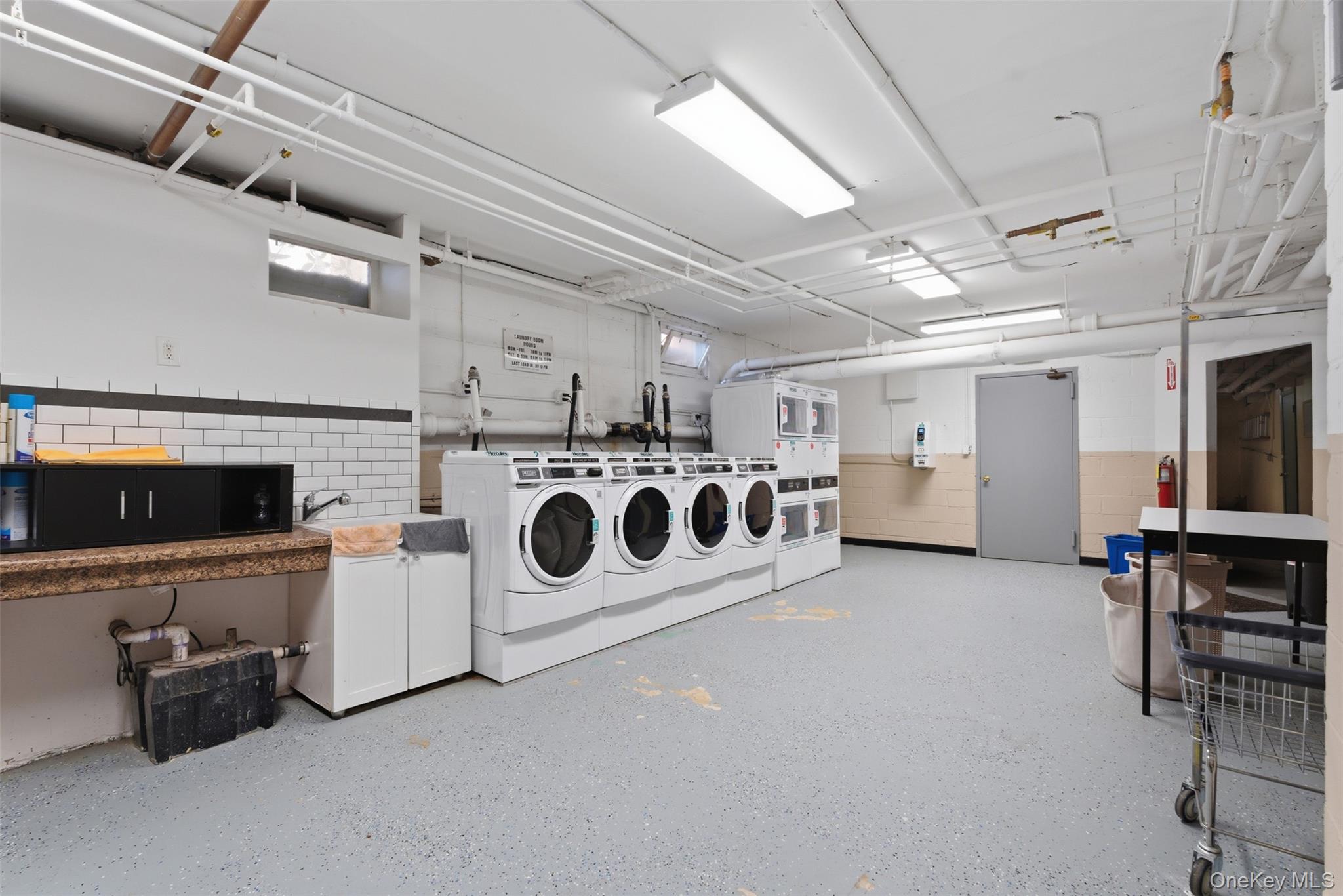 25 Trinity Place, Unit 2K New Rochelle, NY 10805 - Photo 21 of 25 Dedicated laundry facility featuring several washing machines and dryers, a utility sink, and ample counter space for convenience. Machines operated by card.