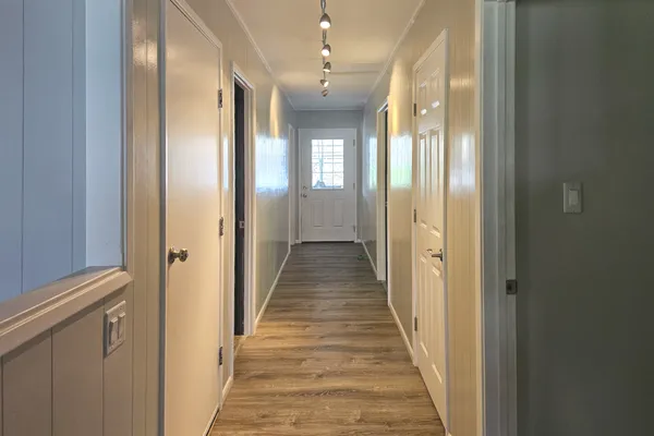 a view of a hallway with wooden floor and a chandelier