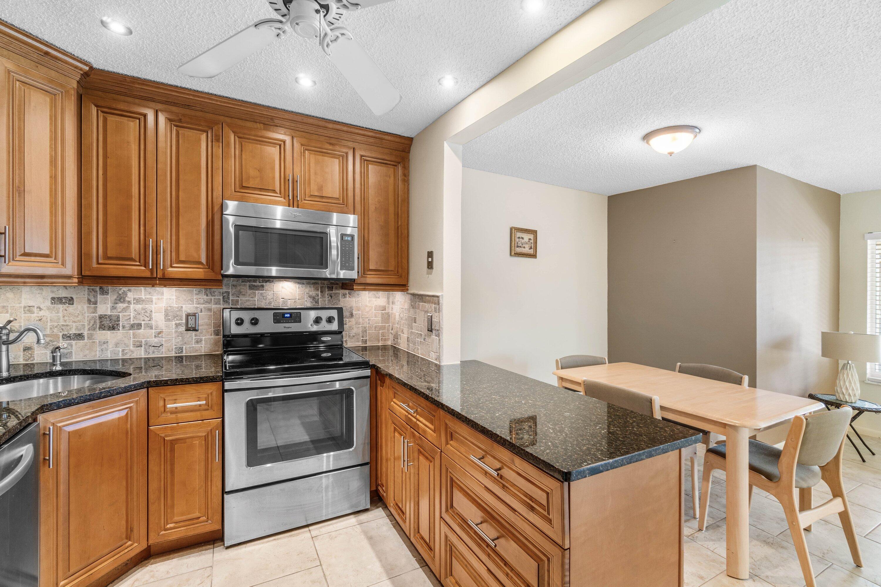 322 Pine Ridge Circle, Unit A2 Greenacres, FL 33463 - Photo 11 of 26 a kitchen with stainless steel appliances granite countertop a stove a sink dishwasher and a microwave oven with cabinets