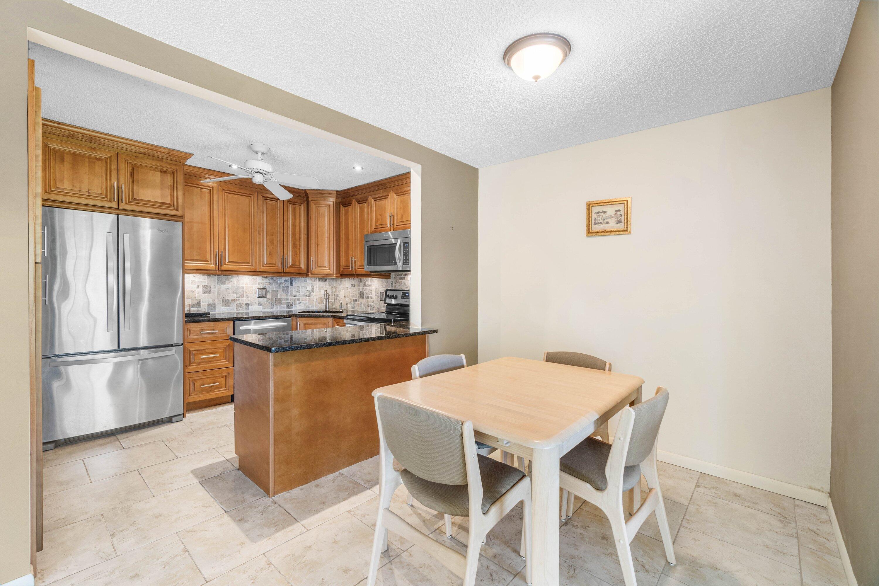 322 Pine Ridge Circle, Unit A2 Greenacres, FL 33463 - Photo 14 of 26 a kitchen with granite countertop a refrigerator and a stove top oven