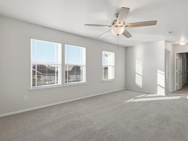 an empty room with chandelier fan and windows