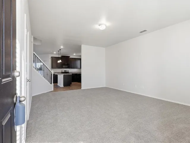 an empty room with kitchen view and a window