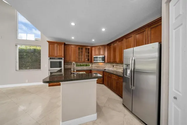 a kitchen with stainless steel appliances granite countertop a refrigerator a stove and a sink