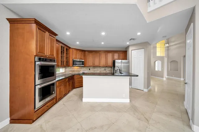 a kitchen with stainless steel appliances granite countertop a refrigerator and a stove top oven