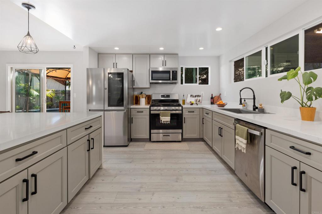 4180 Galbar Place Oceanside, CA 92056 - Photo 13 of 41 a large kitchen with stainless steel appliances granite countertop a sink and dishwasher a stove top oven with wooden floor