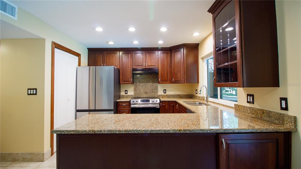1357 Dinsmore Court New Port Richey, FL 34655 - Photo 14 of 60 a kitchen with granite countertop a sink a counter top space cabinets stainless steel appliances and a counter top space