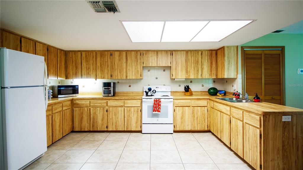1357 Dinsmore Court New Port Richey, FL 34655 - Photo 46 of 60 a kitchen with stainless steel appliances granite countertop a stove top oven a sink a refrigerator and white cabinets