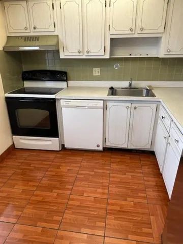 a kitchen with granite countertop a sink a stove and cabinets