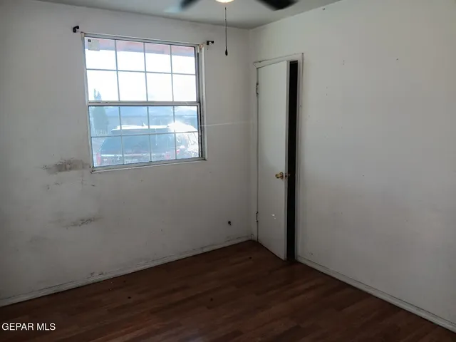 an empty room with wooden floor cabinet and windows