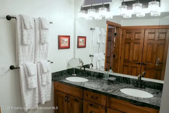 a bathroom with a granite countertop double vanity sink and a mirror