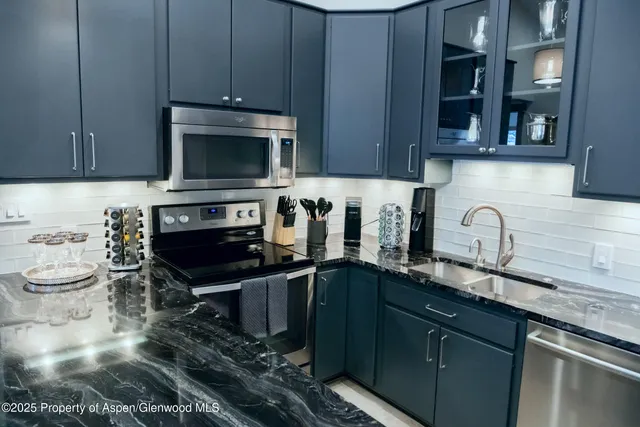 a kitchen with granite countertop a sink stainless steel appliances and cabinets