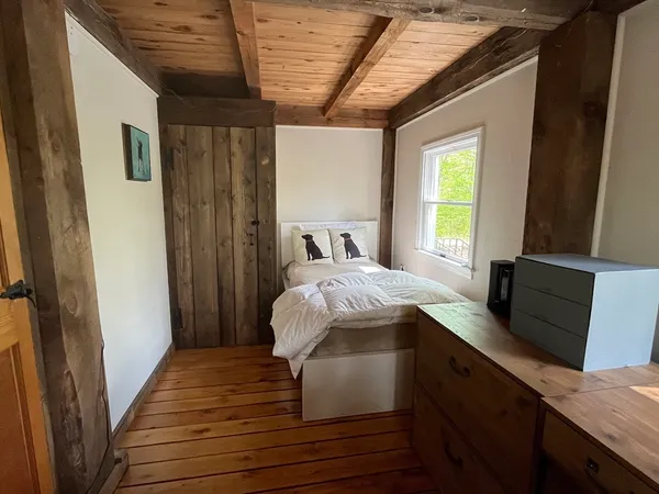 a bedroom with a bed and a dresser next to a window