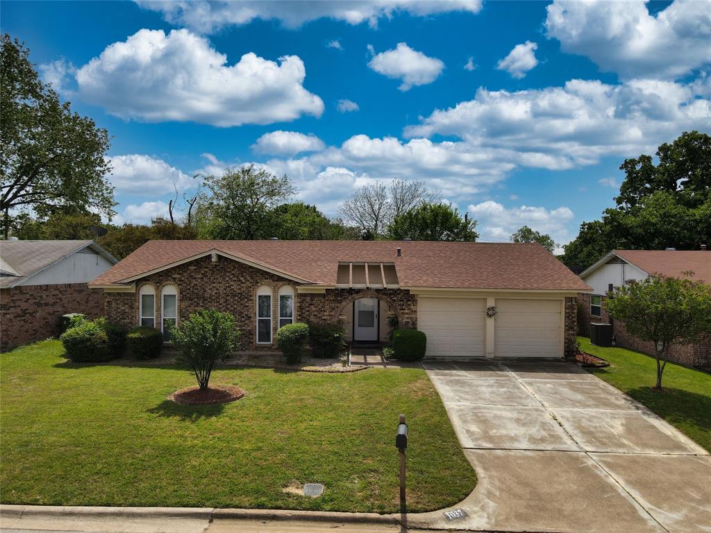 View of front facade featuring a front lawn, concrete driveway, a garage, and brick siding