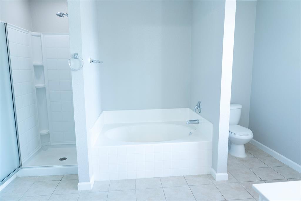 8805 Graywolf Ridge Trail Fort Worth, TX 76244 - Photo 14 of 23 Bathroom featuring a built-in soaking tub with chrome fixtures, a separate shower with clear glass enclosure and tile surround, and light-toned tile flooring