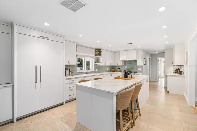 a kitchen with stainless steel appliances a refrigerator a stove top oven and white kitchen island