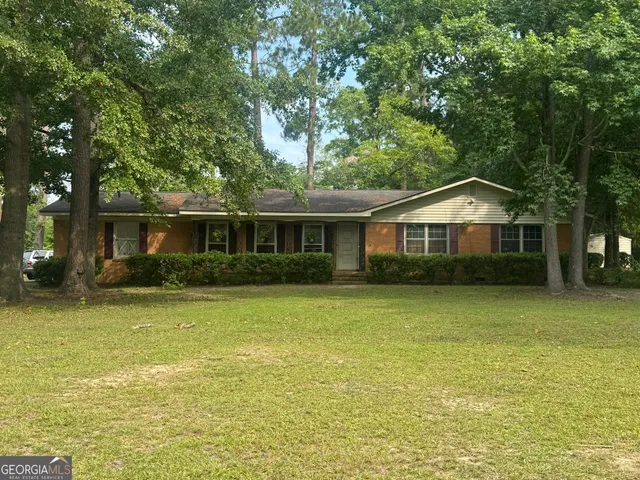 a front view of house with yard and trees in the background