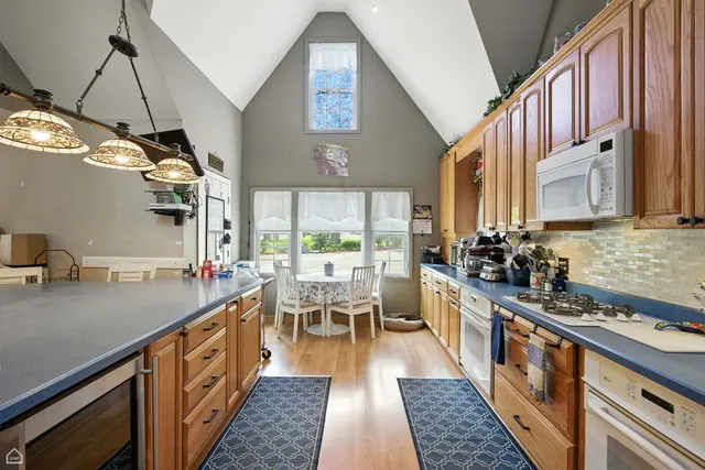 a kitchen with stainless steel appliances granite countertop a stove top oven a sink a dining table and chairs