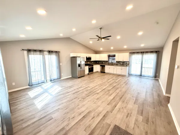 a large kitchen with kitchen island a stove a sink dishwasher and a oven with wooden floor