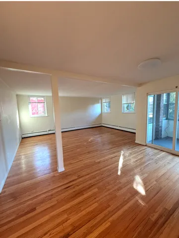 a view of empty room with window and wooden floor