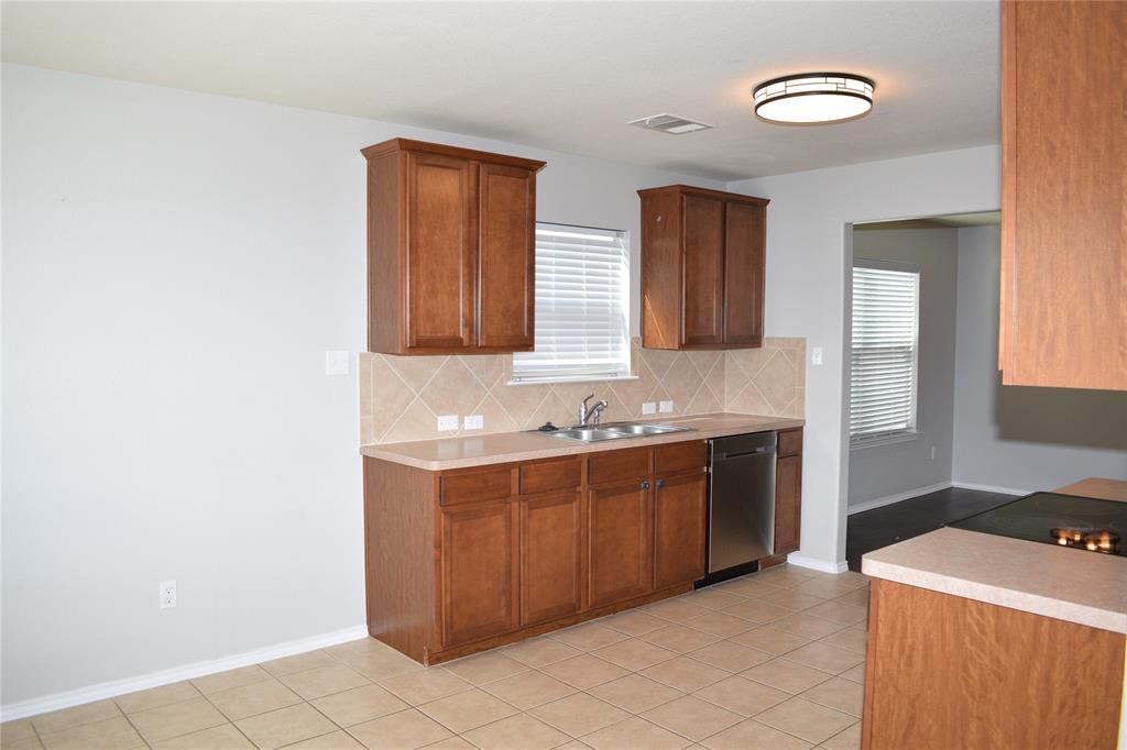 375 Housefinch Loop Leander, TX 78641 - Photo 5 of 28 Rich wood cabinetry and classic tile flooring define this functional cooking space.