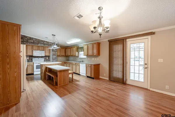 a large kitchen with a center island wooden floor stainless steel appliances and cabinets