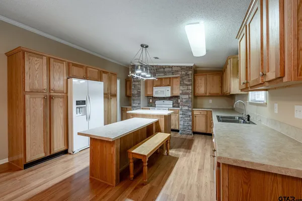 a kitchen with stainless steel appliances granite countertop a refrigerator a sink dishwasher a stove and white countertops with wooden floor