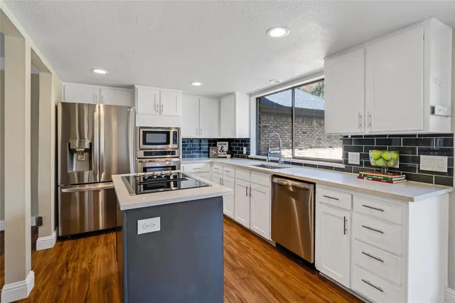a kitchen with kitchen island a refrigerator sink and white cabinets
