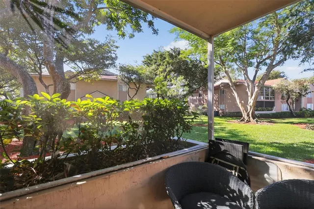 a view of a backyard with table and chairs potted plants and large tree