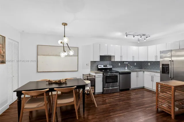 a kitchen with stainless steel appliances kitchen island a dining table and chairs in it