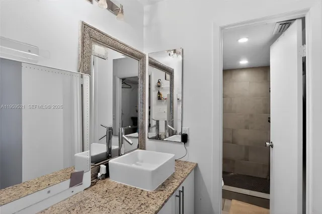 a bathroom with a granite countertop sink a toilet a mirror and shower
