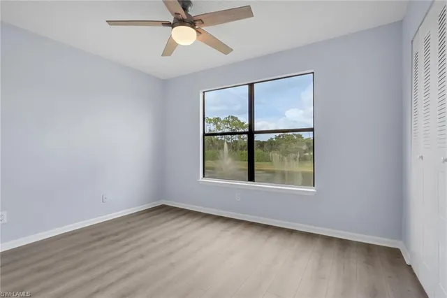 an empty room with wooden floor fan and windows