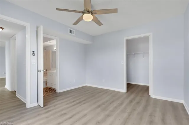 an empty room with wooden floor and a ceiling fan