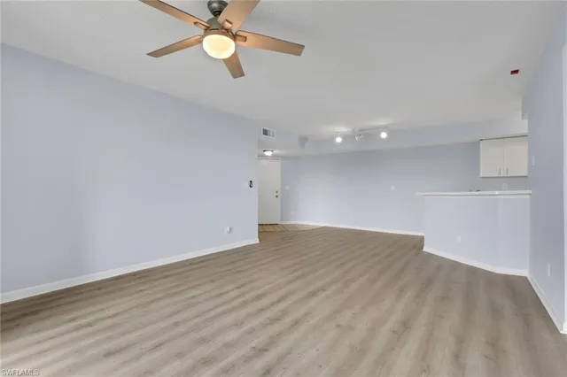 a view of an empty room with window and wooden floor