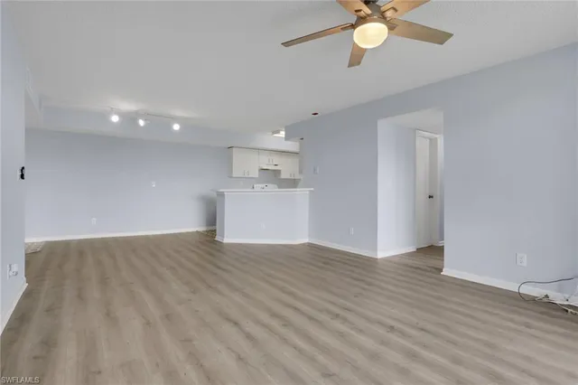 a view of an empty room with a window and wooden floor